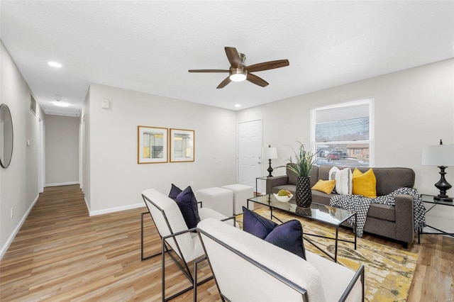 living room with ceiling fan, a textured ceiling, and light hardwood / wood-style flooring