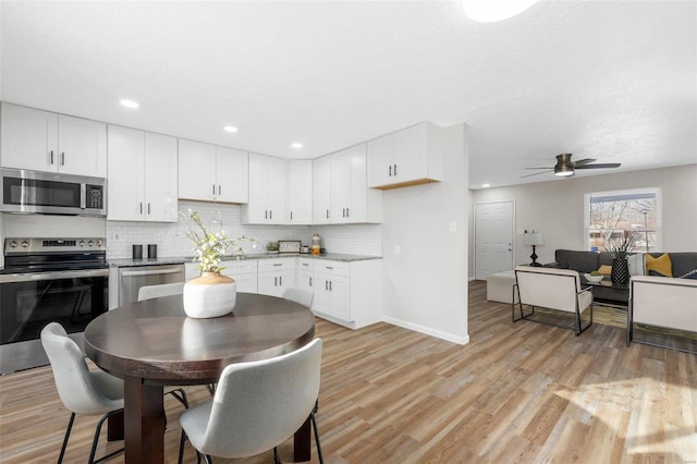 kitchen with light hardwood / wood-style floors, white cabinetry, appliances with stainless steel finishes, and tasteful backsplash