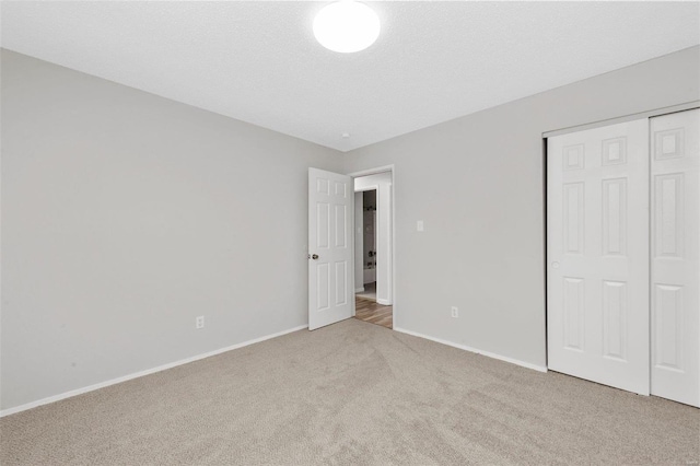 unfurnished bedroom featuring light carpet and a closet