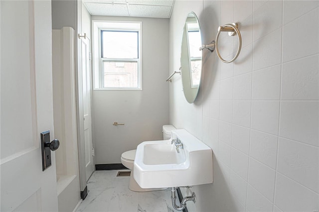 bathroom with toilet, tile walls, a paneled ceiling, and sink