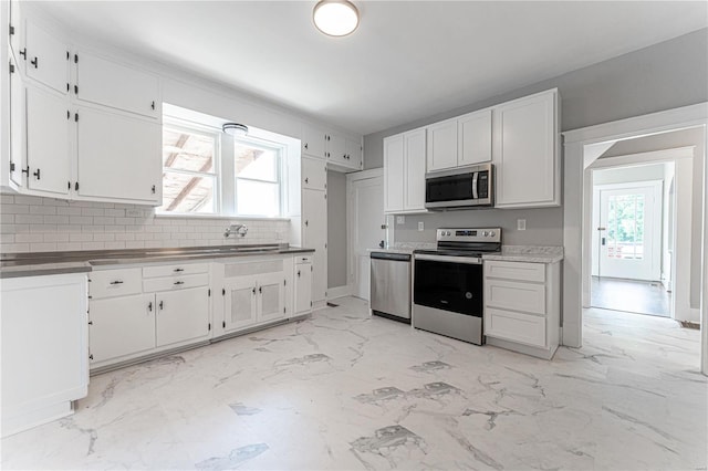 kitchen featuring appliances with stainless steel finishes, tasteful backsplash, white cabinetry, and sink