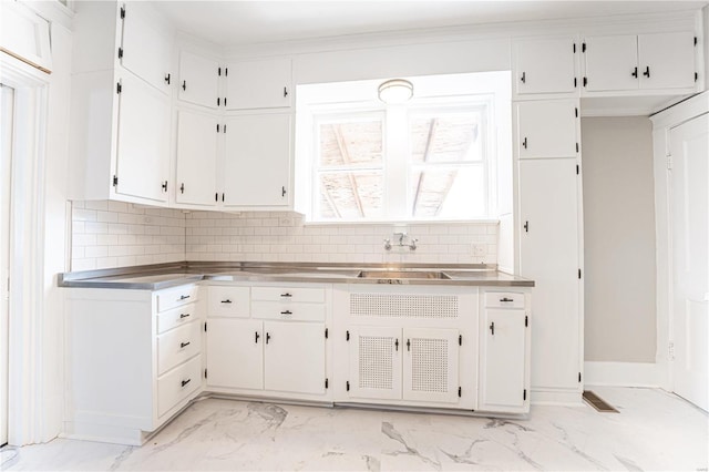 kitchen featuring stainless steel counters, white cabinets, decorative backsplash, and sink