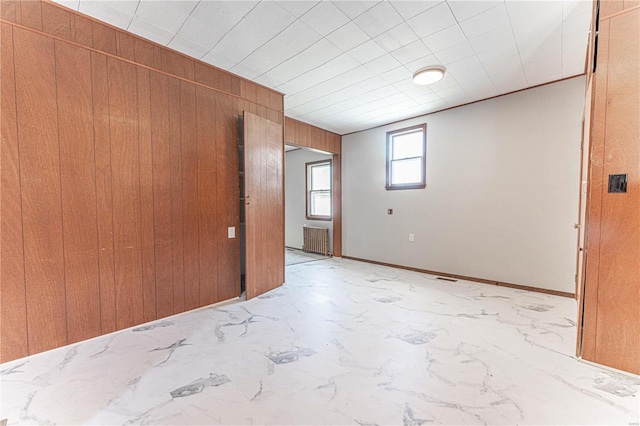 spare room with wood walls and radiator