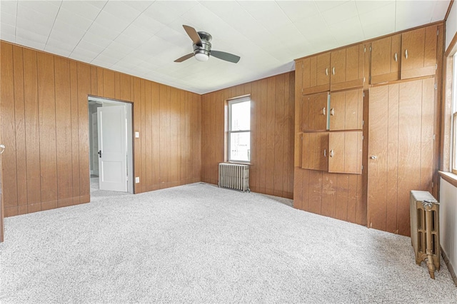 unfurnished bedroom with ceiling fan, radiator heating unit, and light carpet