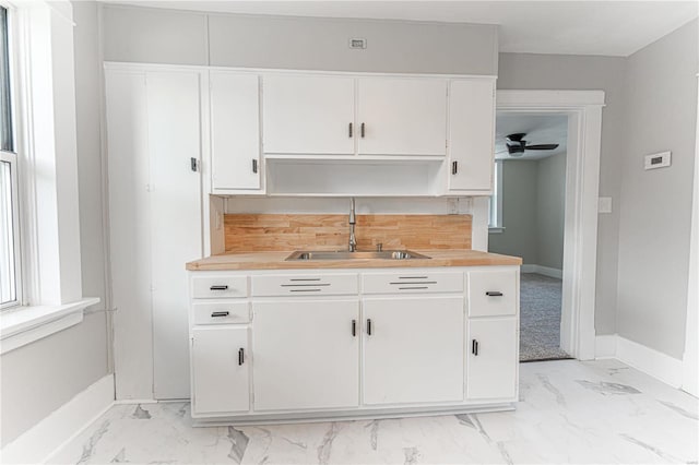 kitchen with sink, ceiling fan, and white cabinets