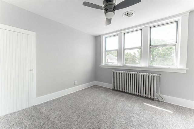 unfurnished room with ceiling fan, radiator heating unit, and carpet flooring