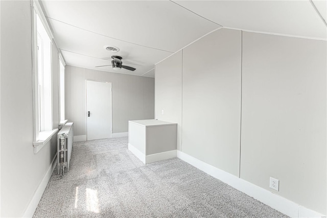 carpeted spare room featuring ceiling fan, vaulted ceiling, and radiator