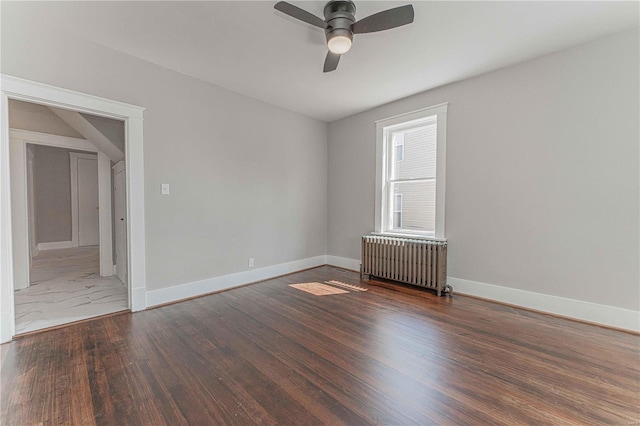 empty room featuring ceiling fan, dark wood-type flooring, and radiator heating unit