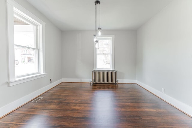 spare room featuring radiator and dark hardwood / wood-style flooring