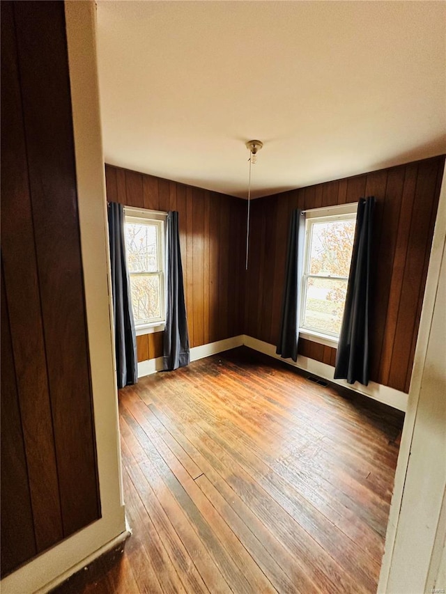 unfurnished room featuring wood walls, light hardwood / wood-style floors, and a wealth of natural light