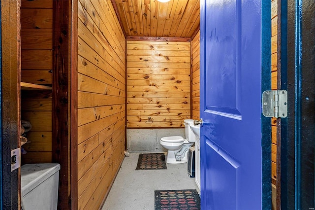 bathroom featuring concrete flooring, wooden ceiling, wooden walls, and toilet