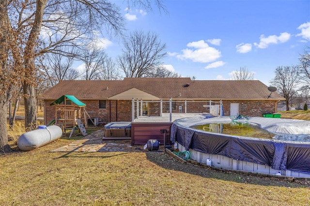 back of property featuring a playground, a pool with hot tub, and a patio