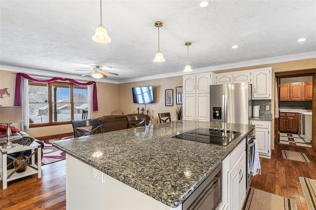 kitchen featuring black electric cooktop, stainless steel fridge, hanging light fixtures, and white cabinets