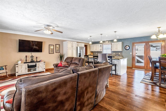 living room with hardwood / wood-style floors, ceiling fan with notable chandelier, ornamental molding, and a textured ceiling