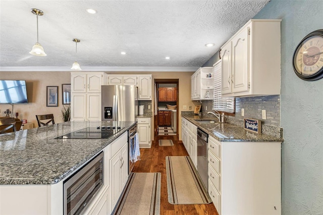 kitchen with sink, white cabinetry, hanging light fixtures, appliances with stainless steel finishes, and dark hardwood / wood-style flooring