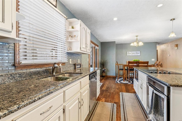 kitchen featuring pendant lighting, sink, appliances with stainless steel finishes, white cabinets, and dark stone counters