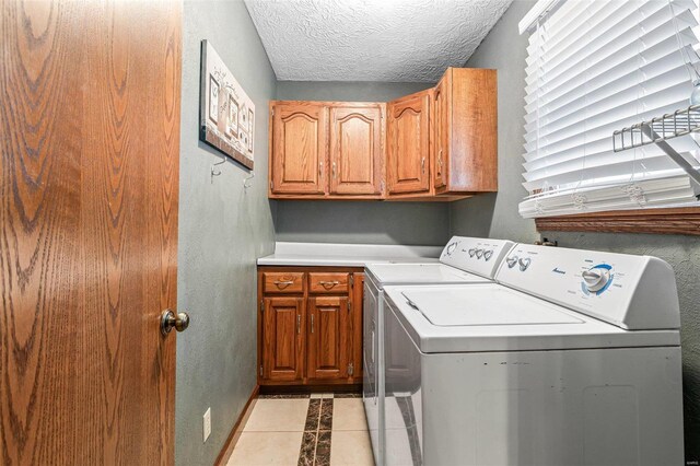 laundry room with cabinets, separate washer and dryer, a textured ceiling, and light tile patterned floors