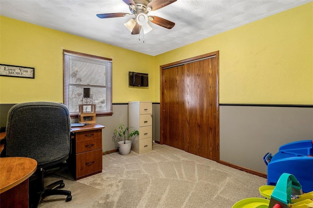 carpeted office space featuring ceiling fan