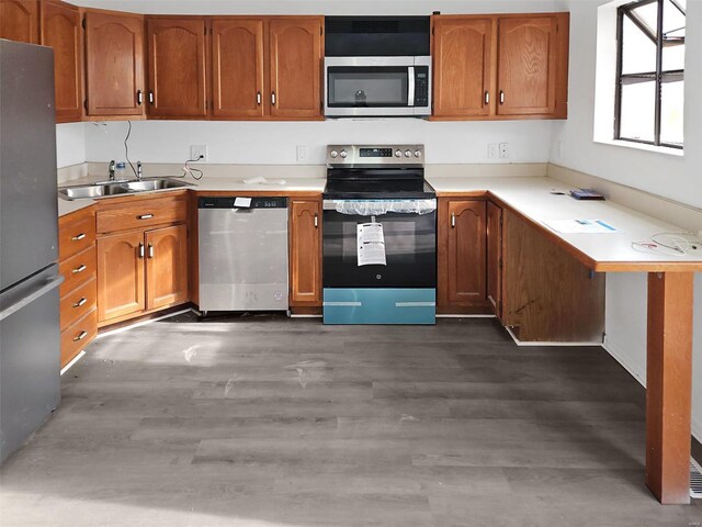 kitchen with appliances with stainless steel finishes, dark wood-type flooring, and sink