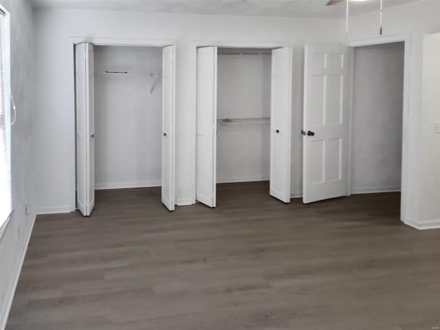 unfurnished bedroom featuring dark hardwood / wood-style floors and multiple closets