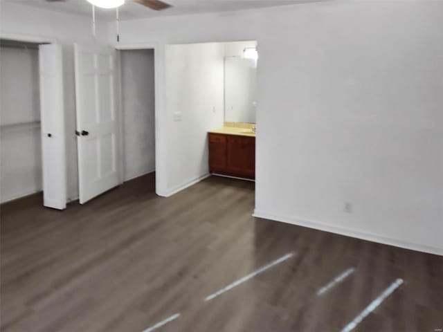 unfurnished bedroom featuring ceiling fan, dark wood-type flooring, and connected bathroom