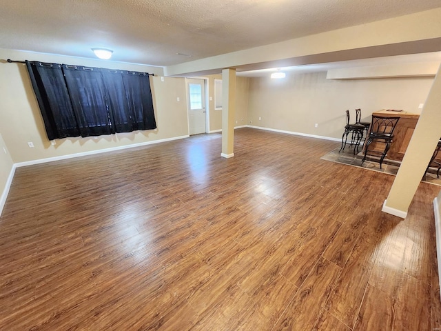 basement with indoor bar, hardwood / wood-style floors, and a textured ceiling