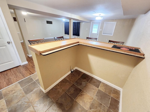 kitchen with hardwood / wood-style flooring, kitchen peninsula, and a textured ceiling