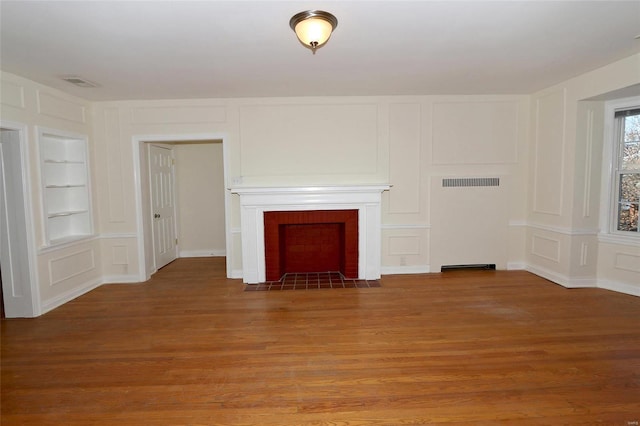 unfurnished living room with wood-type flooring and built in shelves