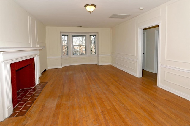 unfurnished living room featuring hardwood / wood-style floors and a tile fireplace