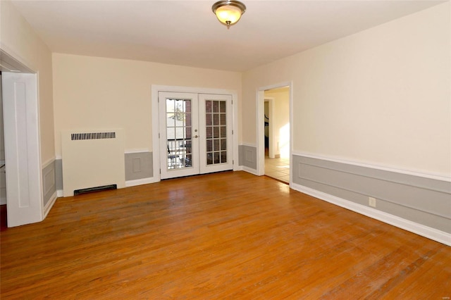 spare room featuring wood-type flooring, radiator heating unit, and french doors