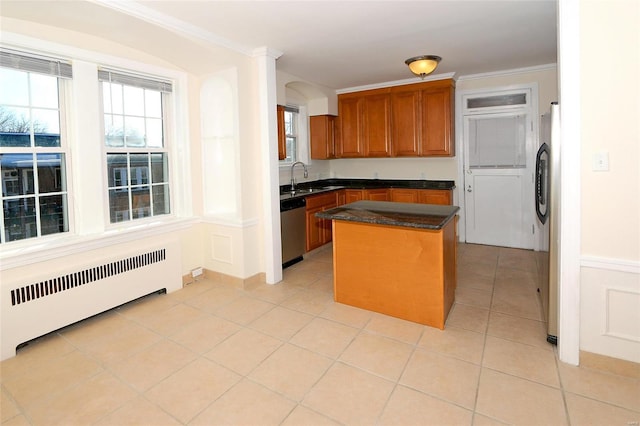 kitchen featuring crown molding, appliances with stainless steel finishes, sink, radiator, and a center island