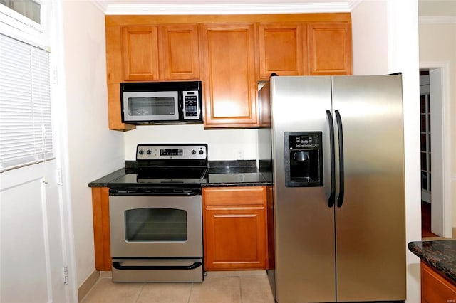 kitchen featuring ornamental molding, stainless steel appliances, dark stone counters, and light tile patterned flooring