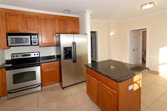 kitchen featuring crown molding, appliances with stainless steel finishes, a kitchen island, dark stone countertops, and light tile patterned flooring