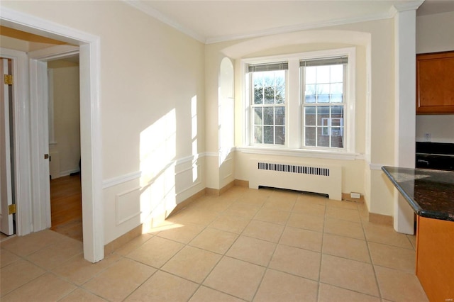 unfurnished dining area featuring radiator heating unit, light tile patterned floors, and ornamental molding