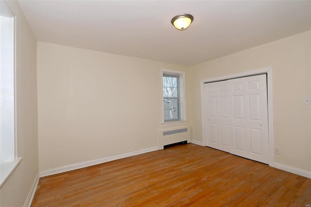 unfurnished bedroom featuring radiator, a closet, and light hardwood / wood-style flooring