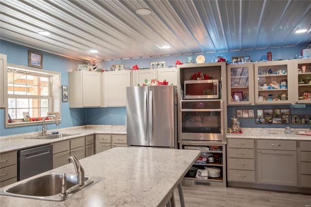 kitchen featuring light stone countertops, sink, light wood-type flooring, and stainless steel appliances