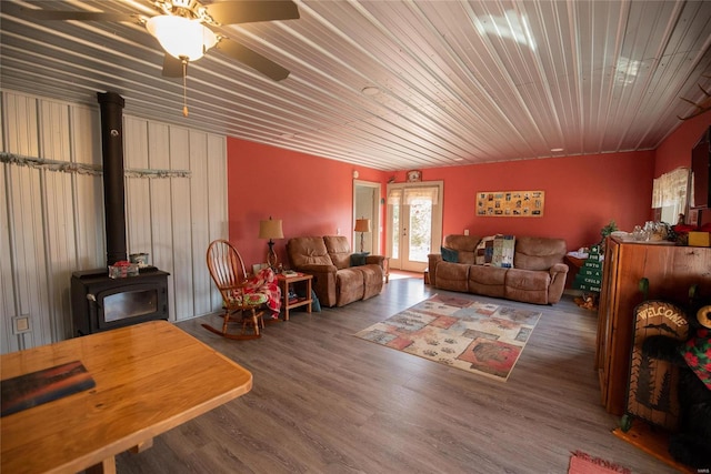 living room featuring a wood stove, ceiling fan, and dark wood-type flooring