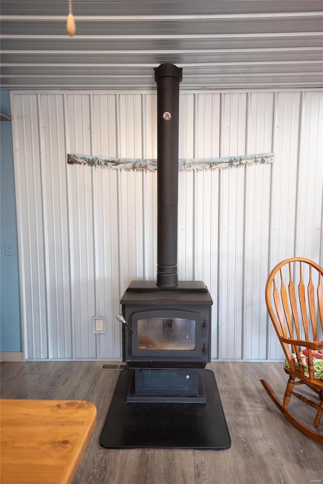 details with a wood stove and wood-type flooring