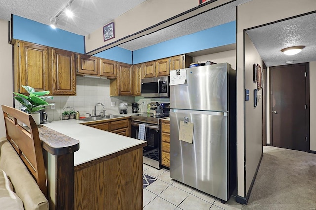 kitchen featuring backsplash, kitchen peninsula, sink, light tile patterned flooring, and stainless steel appliances