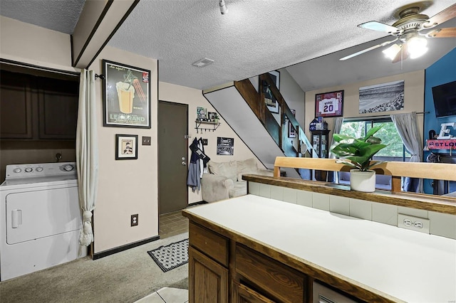 laundry area featuring ceiling fan, washer / dryer, a textured ceiling, and cabinets