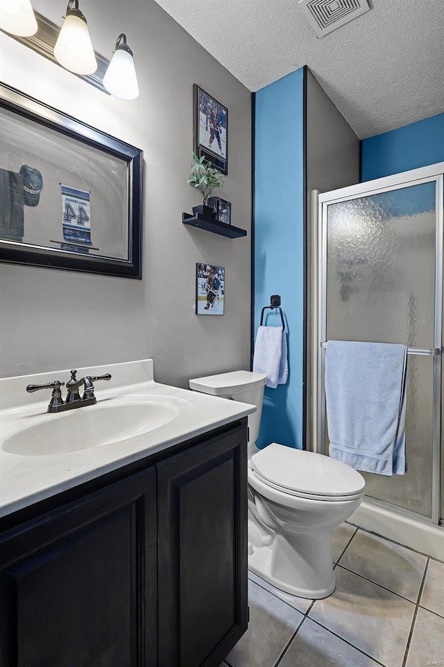 bathroom featuring a textured ceiling, tile patterned floors, a shower with door, vanity, and toilet