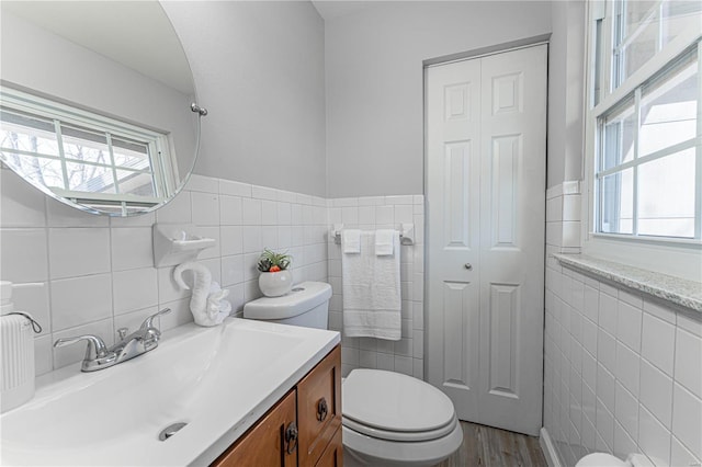 bathroom with hardwood / wood-style flooring, vanity, toilet, and tile walls