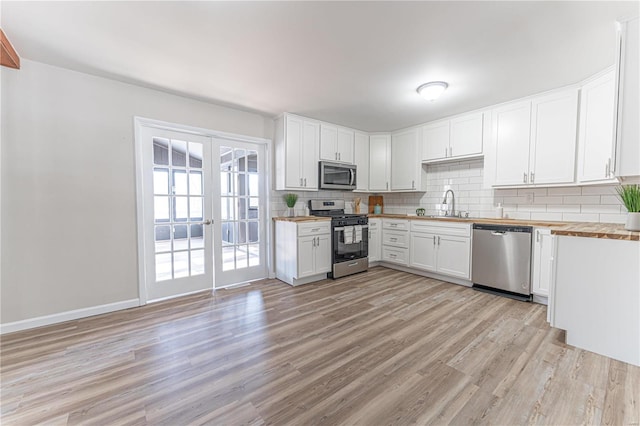 kitchen featuring sink, appliances with stainless steel finishes, butcher block counters, white cabinets, and french doors