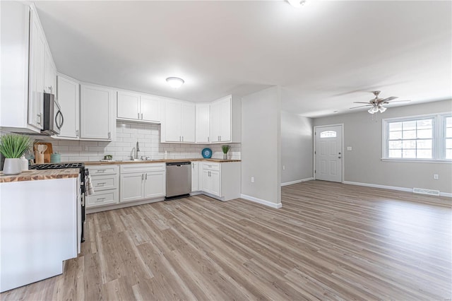 kitchen featuring wood counters, white cabinetry, tasteful backsplash, light wood-type flooring, and stainless steel appliances