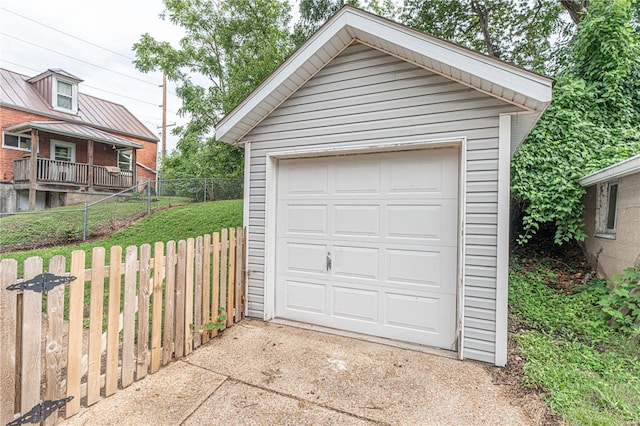 detached garage featuring driveway and fence