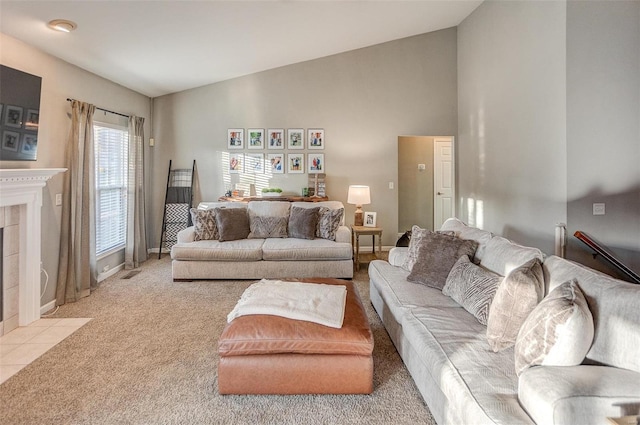 carpeted living room featuring vaulted ceiling and a tiled fireplace