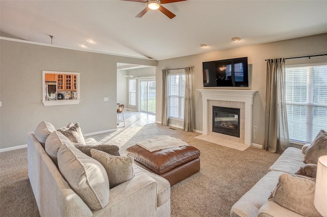 carpeted living room featuring a tile fireplace, ceiling fan, and vaulted ceiling