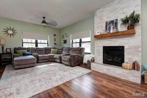 living room featuring ceiling fan, a stone fireplace, wood-type flooring, and a wealth of natural light