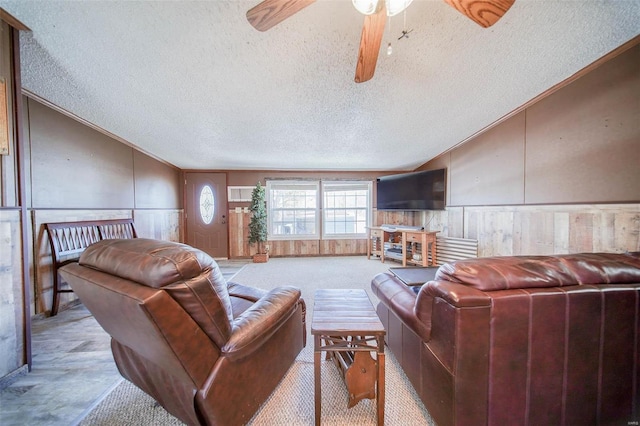 carpeted living room with ceiling fan, a textured ceiling, ornamental molding, and wooden walls