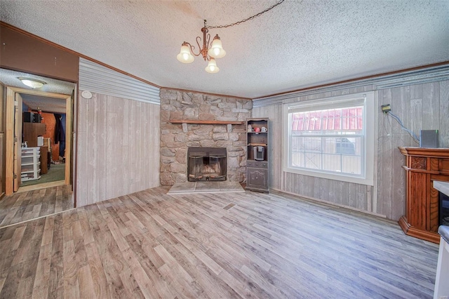 unfurnished living room featuring wooden walls, crown molding, a chandelier, and a fireplace